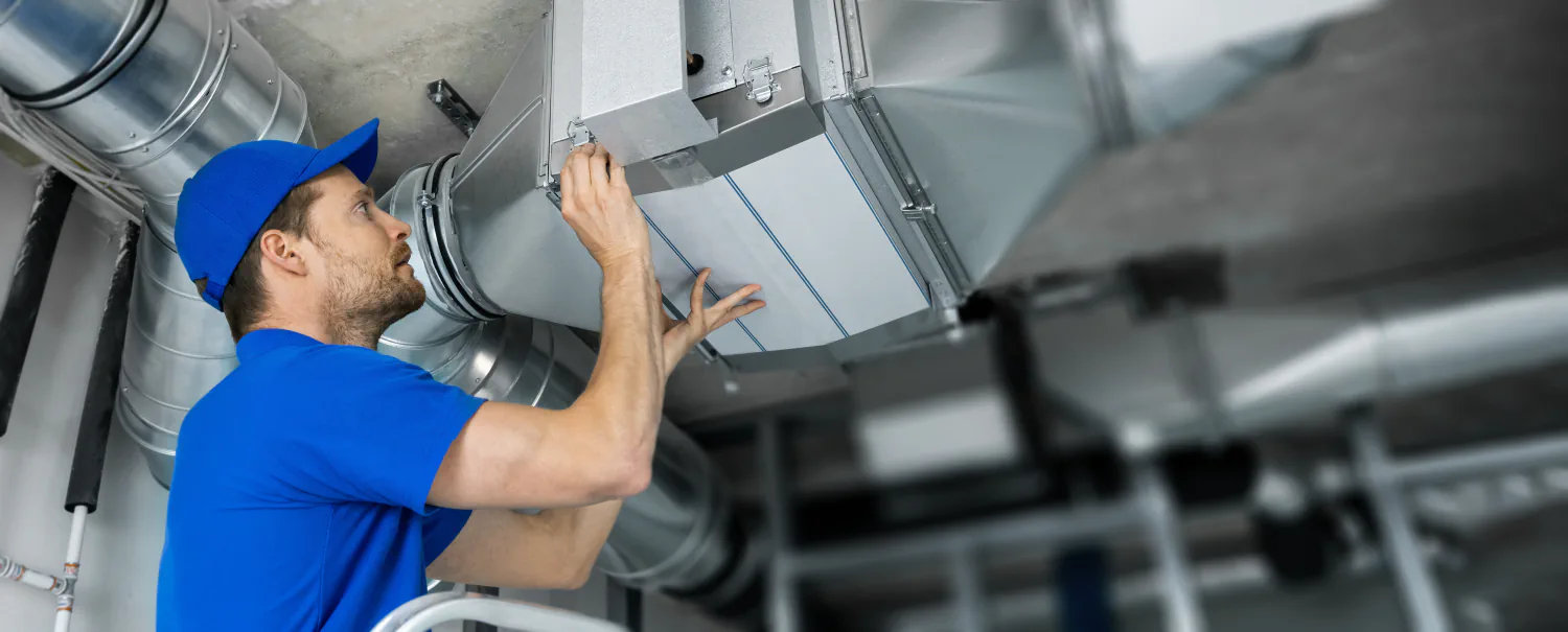 HVAC technician installing an air filter in a commercial ventilation system