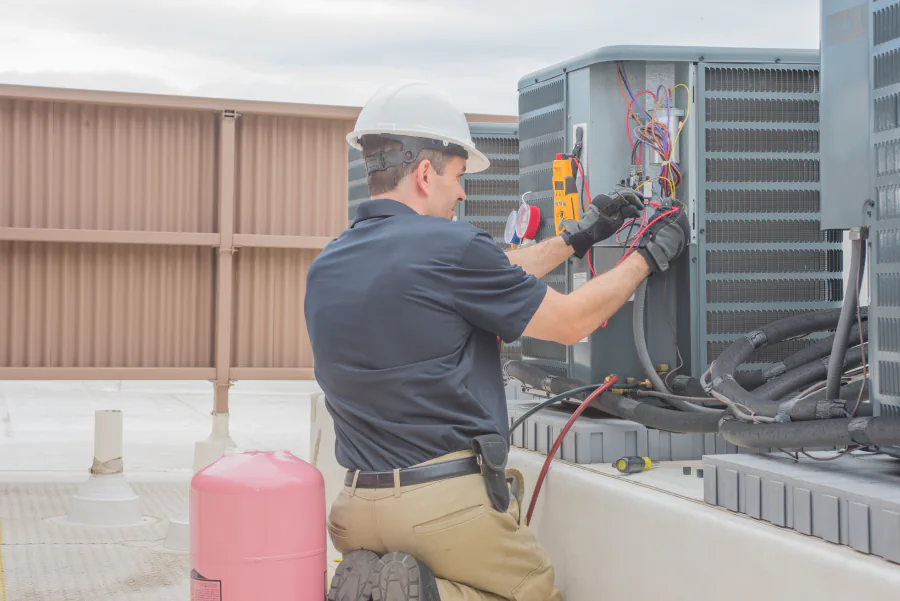 HVAC technician servicing outdoor air-conditioning equipment on a commercial rooftop